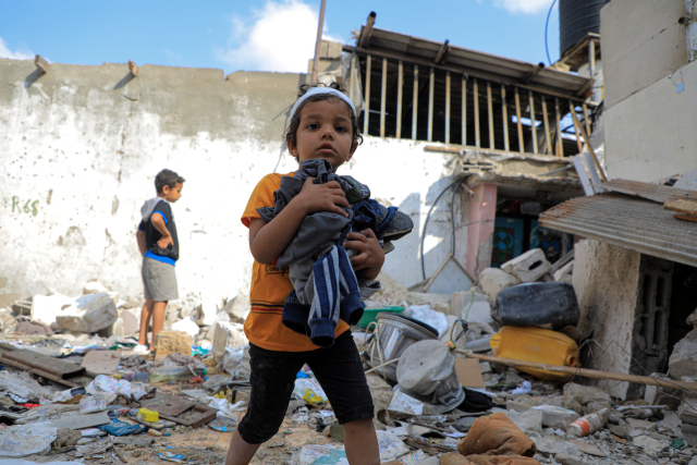 팔레스타인 어린이가 1일(현지시간) 가자지구 남부 도시 라파의 파괴된 주택 잔해 사이에서 옷가지를 줍고 있다. 신화연합뉴스