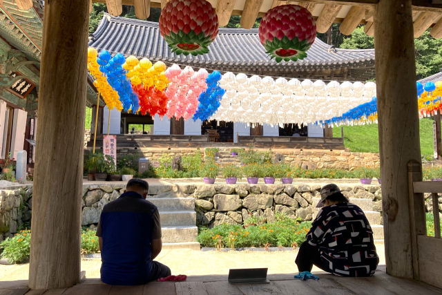 중년 남녀가 봉정사 만세루에 엉덩이를 걸치고 앉아 시원한 바람을 즐기고 있다. 남태우 기자