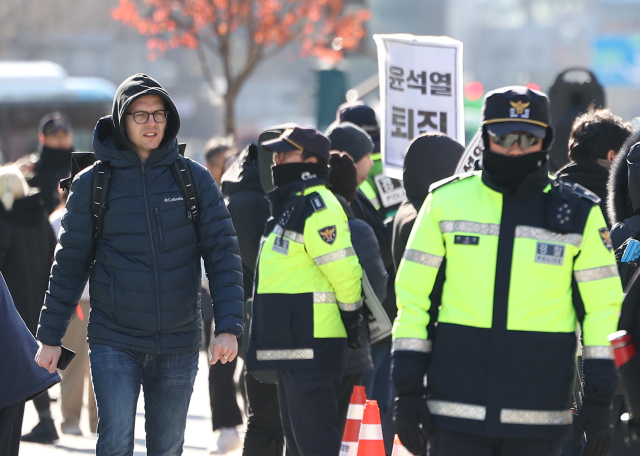 윤석열 대통령이 긴급 대국민 담화를 통해 비상계엄 해제를 선언한 지난 4일 오전 서울 종로구 광화문광장에서 한 외국인 관광객이 계엄 규탄 집회를 지켜보고 있다. 연합뉴스