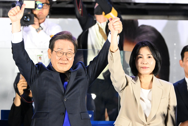 제21대 대통령 당선이 확실시되는 더불어민주당 이재명 대선 후보와 부인 김혜경 여사가 4일 서울 여의도 국회 인근에서 당 주최로 열린 국민개표방송 행사에 참석해 시민들을 향해 두 팔을 들어올려 인사하고 있다. 연합뉴스
