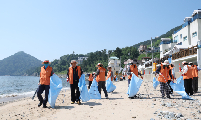 한화오션 임직원이 6월 26일 거제시 흥남 해수욕장에서 지역 주민들과 함께 해양환경 정화 활동 ‘오션 플로깅’을 진행하고 있다. 한화오션 제공