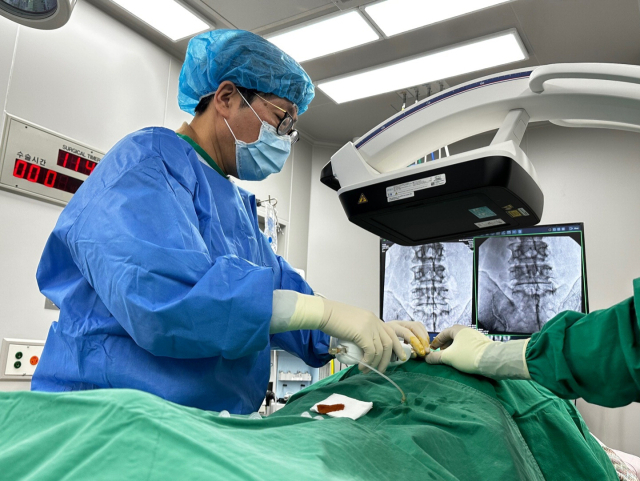 이샘병원 신경외과 박종훈 원장이 허리 디스크 환자에게 신경성형술로 비수술적 치료를 시행하고 있다. 이샘병원 제공