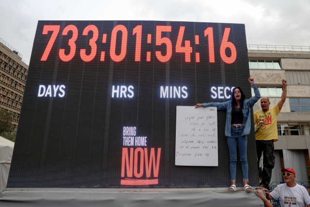 팔레스타인 무장정파 하마스에 납치된 한 인질 가족이 가자전쟁 휴전 협정 1단계 합의 소식이 전해진 9일(현지 시간) 이스라엘 텔아비브 인질 광장에서 시민들이 손을 들어보이고 있다. 로이터연합뉴스