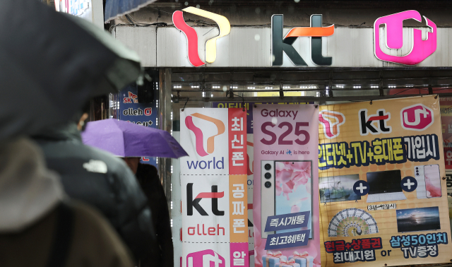 휴대전화를 개통할 때 신분증만 제시하던 것에서 패스 앱을 이용해 얼굴 사진을 찍어 본인임을 확인받는 절차가 시범 실시되는 23일 서울의 한 휴대폰 매장 앞을 시민들이 오가고 있다. 연합뉴스