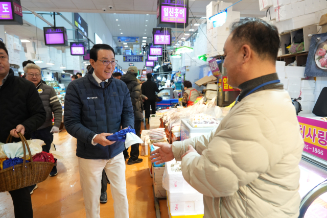 노동진 수협중앙회장(왼쪽)이 지난 10일 서울 동작구 노량진수산시장을 방문해 수산물 판매와 시장 발전에 힘쓰고 있는 시장 상인들에게 감사의 뜻을 담아 설 격려 엽서, 떡, 핸드크림 등이 담긴 복주머니를 전달하고 있다. 수협 제공