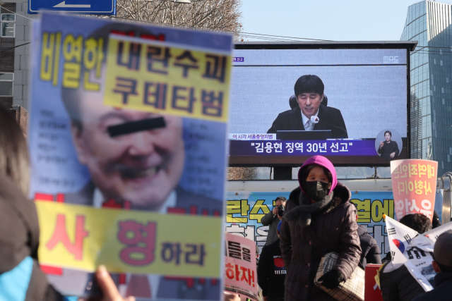 촛불행동 관계자들이 19일 서울 서초구 서울중앙지법 인근에서 12·3 비상계엄과 관련해 내란 우두머리 혐의로 기소된 김용현 전 국방부 장관에 대한 1심 선고 생중계를 시청하고 있다. 이날 재판부는 김 전 장관에게 징역 30년을 선고했다. 연합뉴스