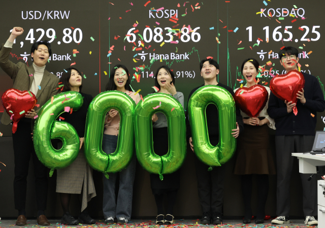 코스피가 사상 처음으로 6000을 돌파해 거래를 마친 25일 서울 중구 하나은행 딜링룸에서 딜러들이 기념 세리머니를 하고 있다. 연합뉴스