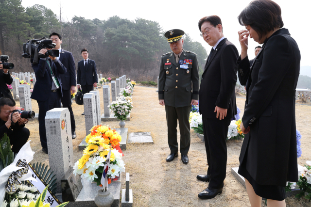 이재명 대통령과 김혜경 여사가 27일 국립대전현충원에서 서해수호의 날 기념식 전 채수근 상병의 묘역을 살펴보고 있다. 왼쪽은 주일석 해병대사령관. 연합뉴스