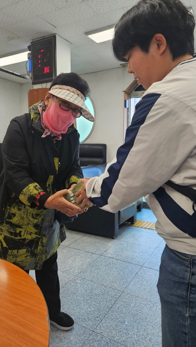 부산 강서경찰서 소속 형사가 피해자 할머니에게 A 씨로부터 압수한 1100만 원의 피해금을 전달하는 모습. 부산 강서경찰서 제공