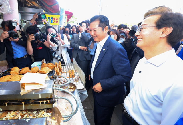 더불어민주당 정청래 대표와 전재수 부산시장 후보가 지난 15일 부산 부산진구 부전시장을 돌며 상인들에게 인사하고 있다. 연합뉴스